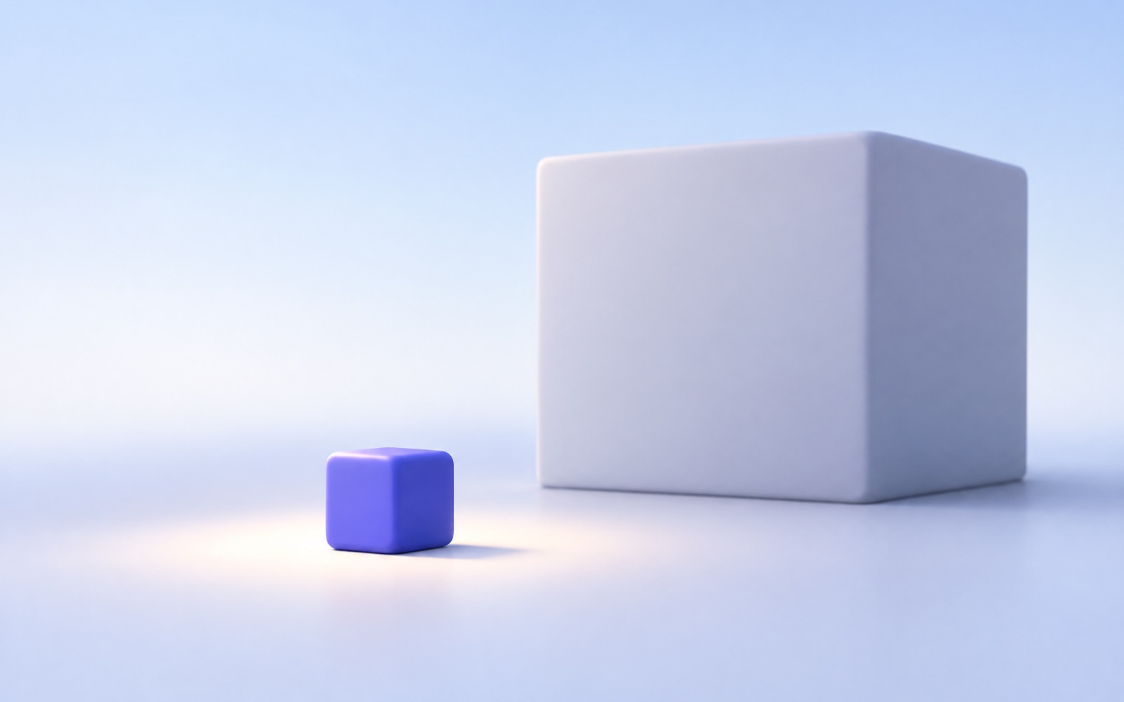 A small indigo cube in a spotlight in front of a large plain grey block
